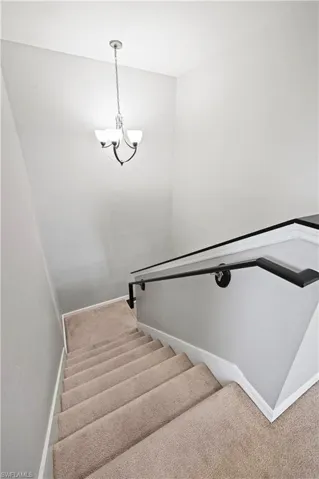 Staircase with carpet floors and an inviting chandelier