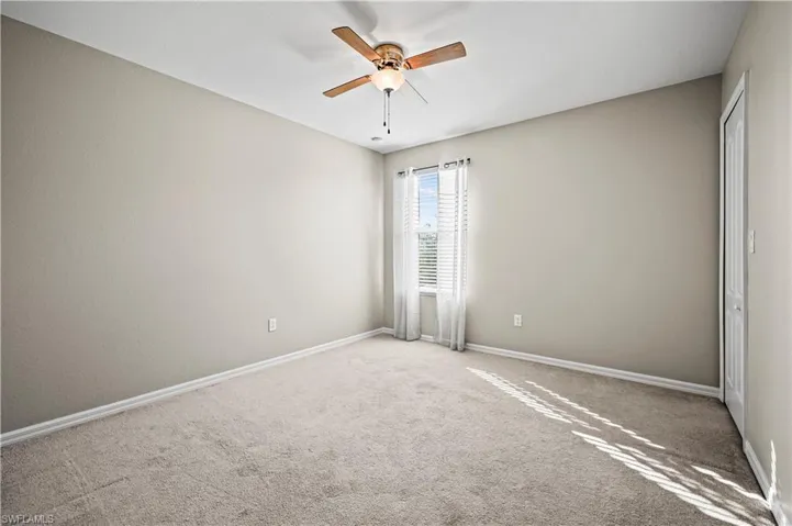 Carpeted spare room featuring ceiling fan