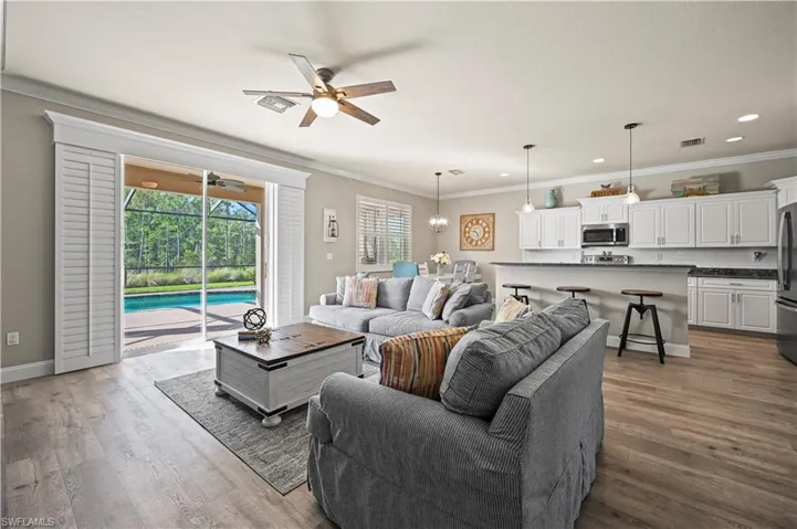 Living room featuring ornamental molding, ceiling fan, and dark wood-type flooring