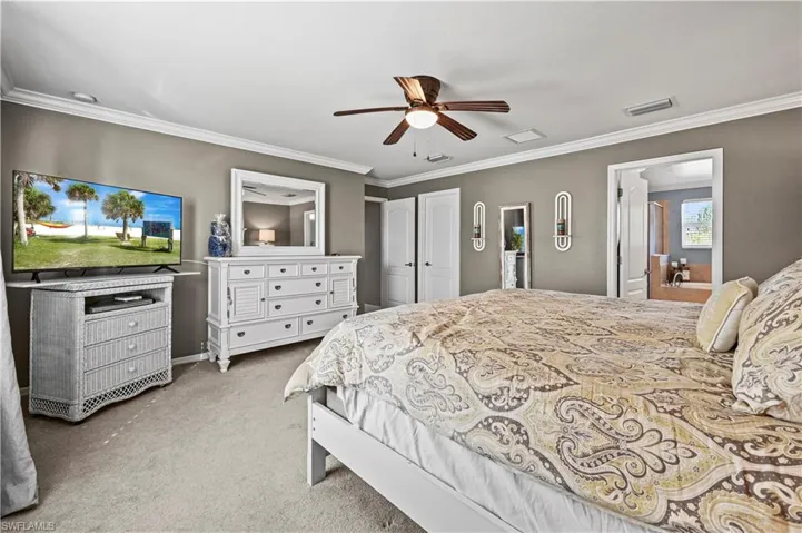 Carpeted bedroom featuring crown molding and ceiling fan