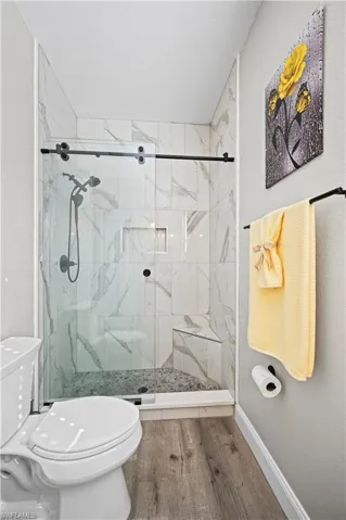 Bathroom featuring toilet, an enclosed shower, and hardwood / wood-style floors