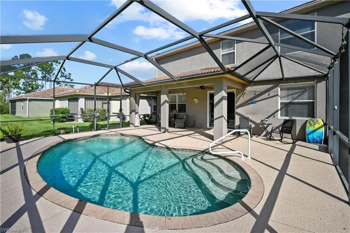 View of swimming pool featuring a patio, glass enclosure, and ceiling fan