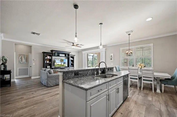 Kitchen with sink, stone countertops, wood-type flooring, and ceiling fan with notable chandelier