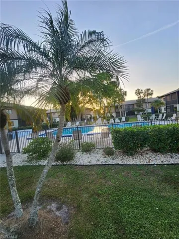 View of property's community with a swimming pool, fence, and a lawn