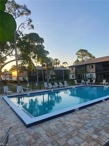 Pool at dusk featuring a patio, fence, and a community pool