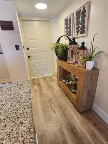 Doorway with light wood-type flooring and baseboards