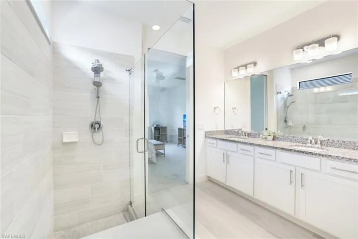Glass-enclosed shower with tiled walls and a dual-head shower system