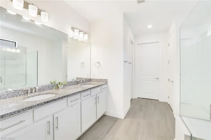 Spacious bathroom featuring a dual vanity with granite countertops, undermount sinks, and ample storage cabinetry