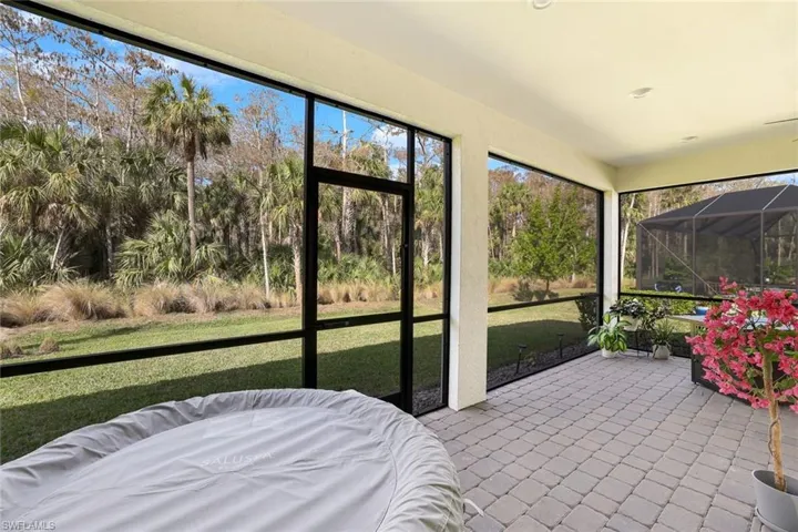 Screened lanai featuring paver flooring and an outdoor spa