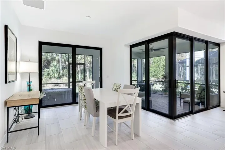Light-toned tile flooring throughout an open dining area with multiple black-framed glass sliding doors leading to an outdoor space
