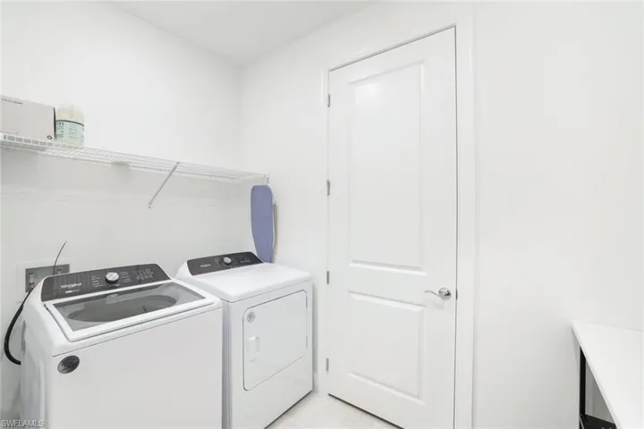 Dedicated laundry area featuring a wire shelving unit, white walls, and a paneled interior door with a chrome knob