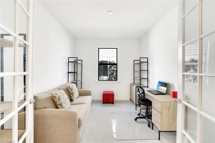 Light-filled room featuring double French doors with clear glass panes, a single window with black framing, and neutral-toned wall-to-wall carpeting