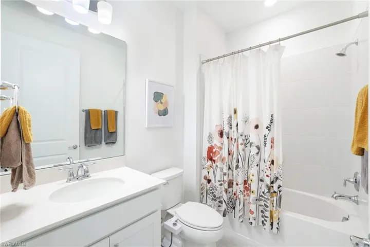 Bathroom featuring a white vanity with an integrated sink, polished chrome faucet, and a large unframed mirror