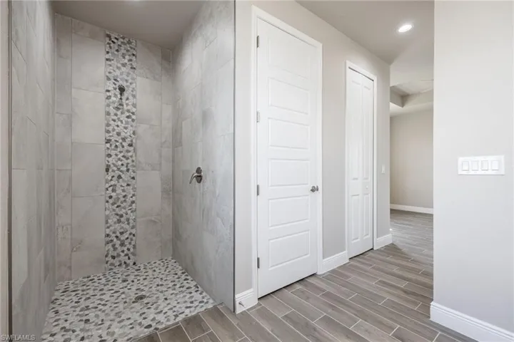 Bathroom featuring a stall shower, wood tiled floors, and recessed lighting-Finishes may vary