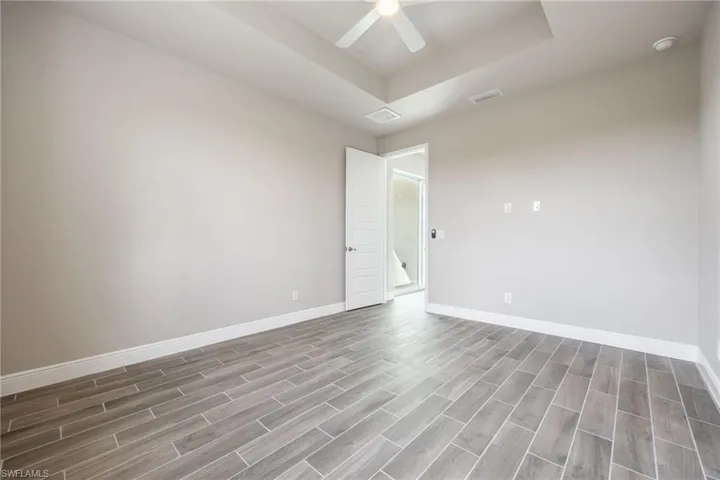 Spare room with a tray ceiling, wood tiled floors, and ceiling fan-Finishes may vary