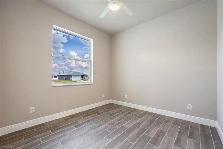 Unfurnished room featuring baseboards and wood tiled floors-Finishes may vary
