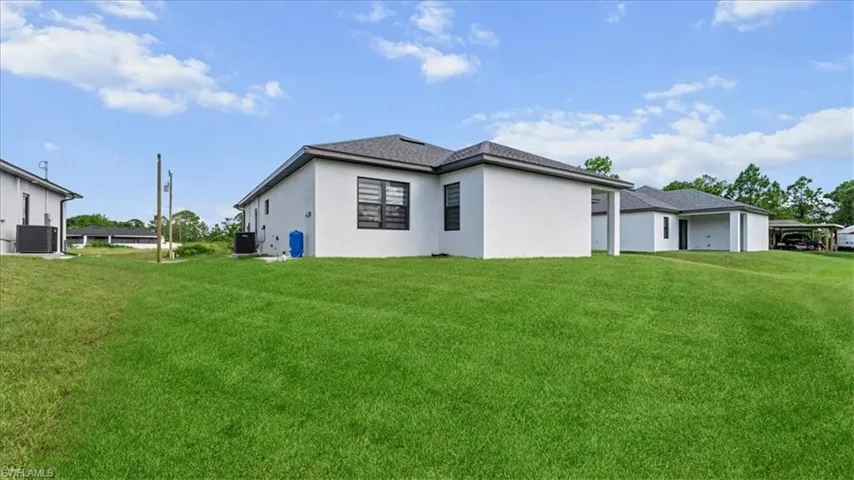 Rear view of property featuring a yard and stucco siding