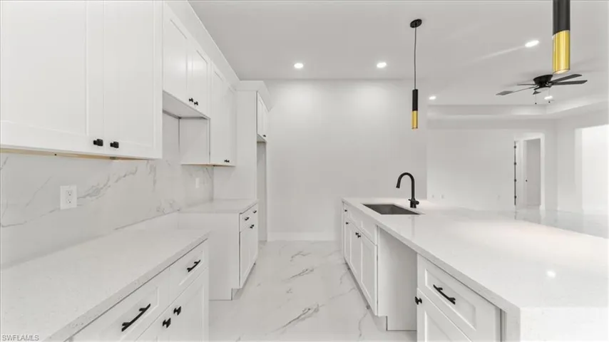 Kitchen featuring white cabinetry, light stone counters, recessed lighting, decorative backsplash, and ceiling fan