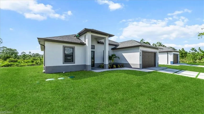 Prairie-style home featuring stucco siding, a front yard, concrete driveway, a garage, and roof with shingles