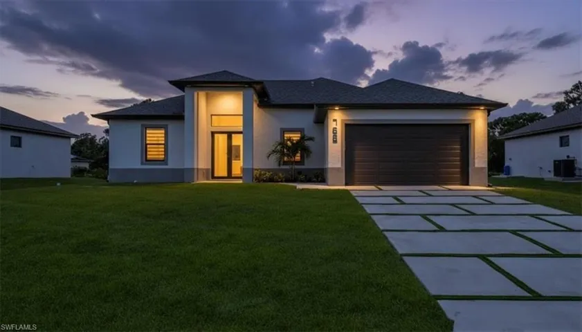 View of front of home featuring stucco siding, a front yard, concrete driveway, and a garage