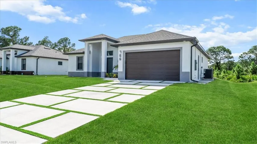 Prairie-style home with stucco siding, a front lawn, driveway, and a garage