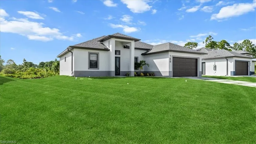 Prairie-style house featuring a front lawn, stucco siding, a garage, and driveway
