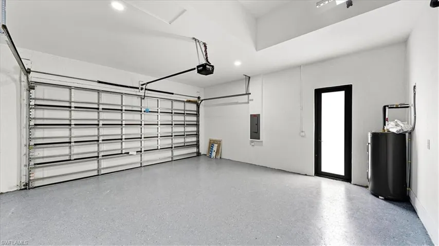Garage featuring recessed lighting, electric panel, and water heater