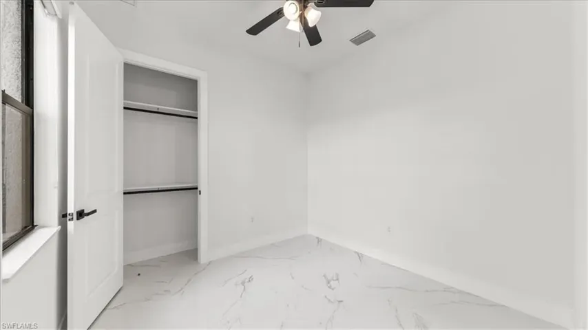 Unfurnished bedroom with ceiling fan and light marble finish flooring