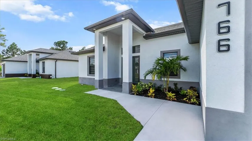 Doorway to property featuring a lawn and stucco siding