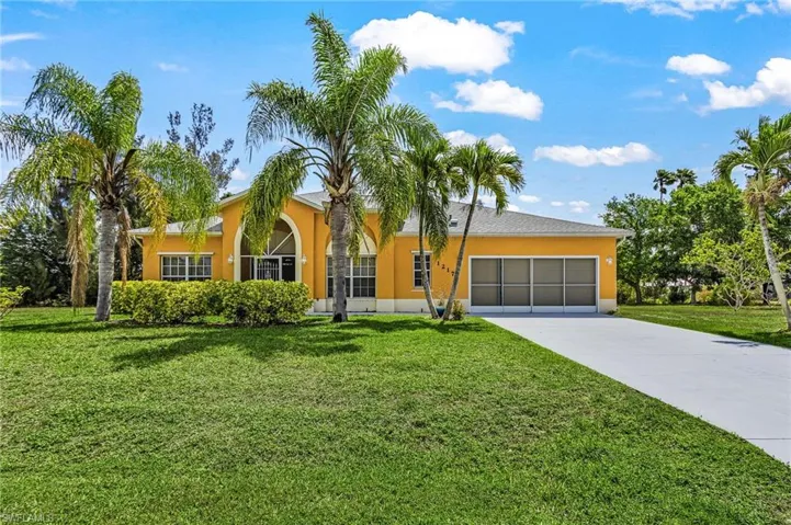 Inviting front exterior framed by mature palms, a lush lawn, and timeless Florida charm.