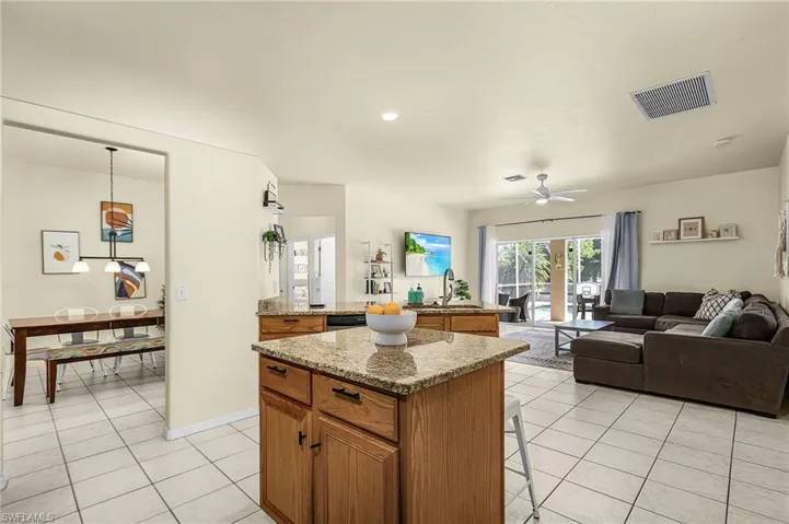 Open-concept living with a spacious kitchen, granite island, tile flooring, and seamless flow into the living and dining areas.