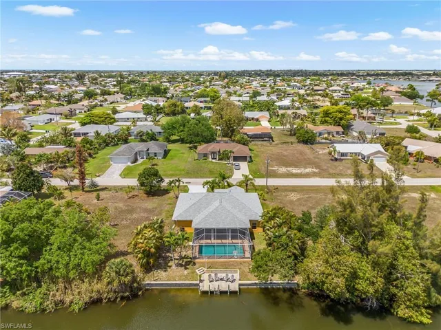 Bird’s-eye view of this Cape Coral waterfront property featuring direct canal access, private dock, screened lanai with pool, and a large backyard