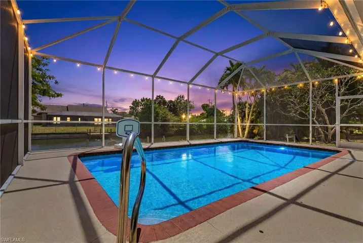 Screened-in pool overlooking canal views in Cape Coral, featuring a private lanai, sparkling pool, and peaceful waterfront setting perfect for relaxing or entertaining at sunset.