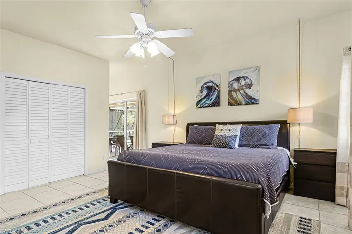 Primary bedroom featuring dual closets and direct access to the screened lanai, enhancing indoor-outdoor living.