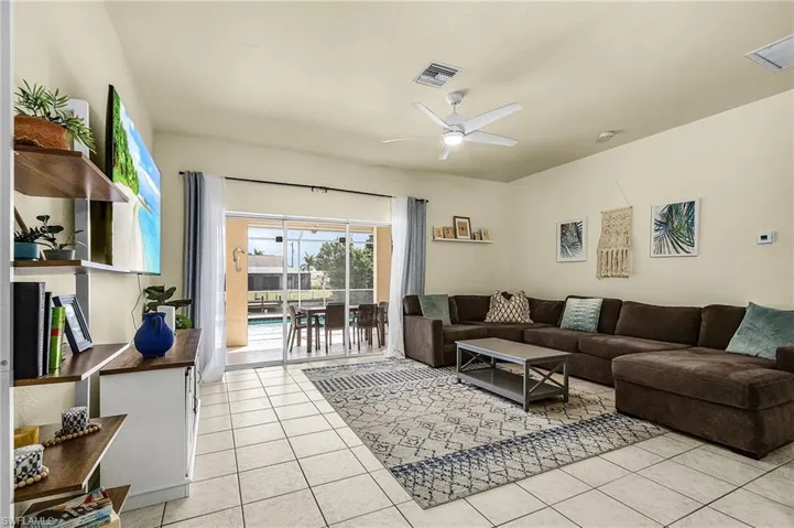 Spacious living room with sliding glass doors opening to the screened lanai and pool, creating seamless indoor-outdoor living