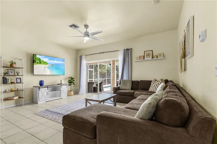 Spacious living room with abundant natural light and sliding doors leading to the screened lanai and pool.