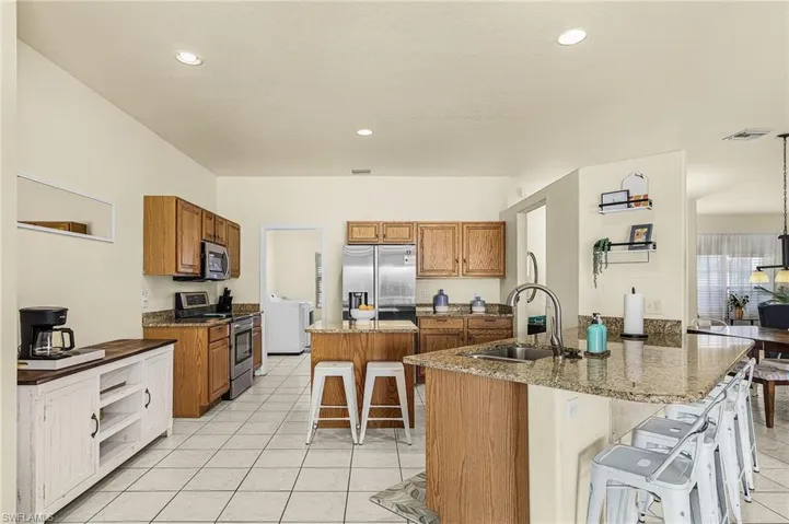 Spacious kitchen featuring granite countertops, stainless steel appliances, ample cabinetry, and multiple prep areas designed for everyday living and entertaining.