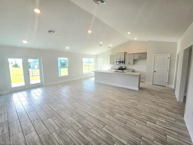 Unfurnished living room featuring lofted ceiling and light hardwood / wood-style floors