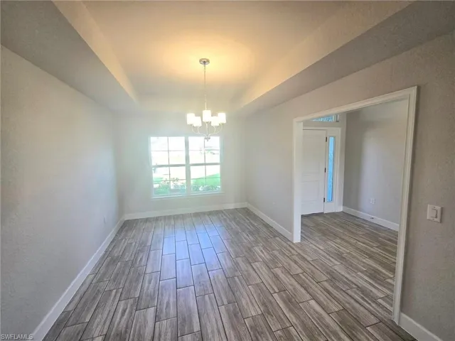Empty room featuring light hardwood / wood-style flooring and a notable chandelier