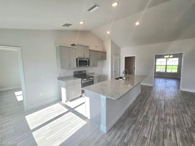 Kitchen featuring lofted ceiling, sink, appliances with stainless steel finishes, and light wood-type flooring