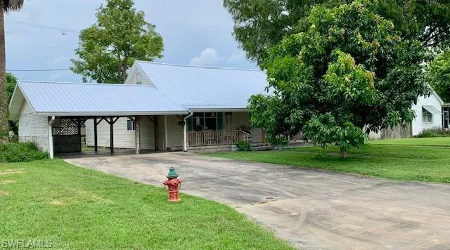 View of front of house with a carport, a porch, and a front lawn