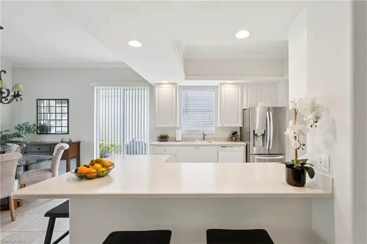 Kitchen featuring a kitchen breakfast bar, stainless steel fridge with ice dispenser, ornamental molding, a peninsula, and recessed lighting