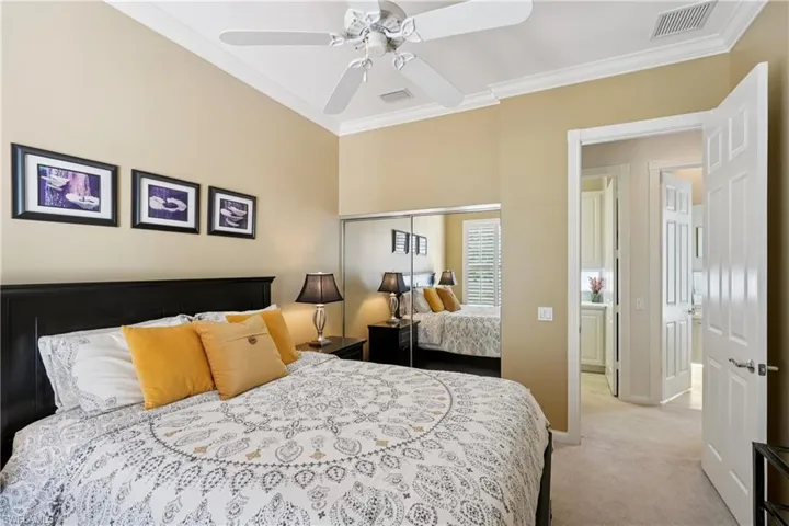 Bedroom with crown molding, light carpet, ceiling fan, and a closet