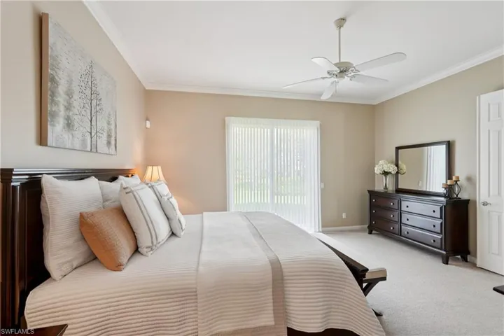 Carpeted bedroom with crown molding and a ceiling fan