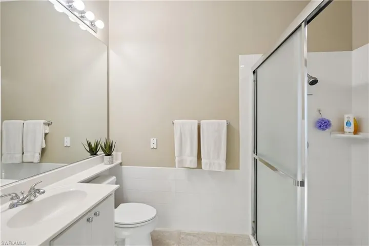 Full bath featuring vanity, tile walls, a shower stall, wainscoting, and light tile patterned floors