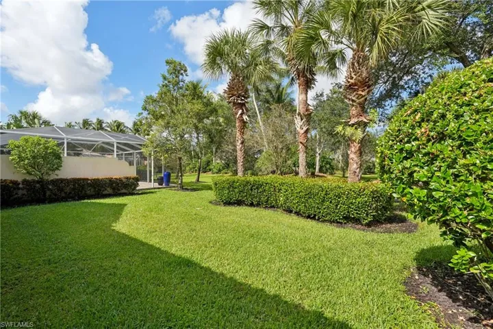 View of grassy yard featuring a sunroom and glass enclosure