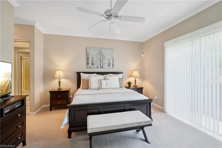 Bedroom with crown molding, light colored carpet, and a ceiling fan