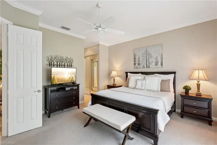 Bedroom with crown molding, light carpet, a closet, and a ceiling fan