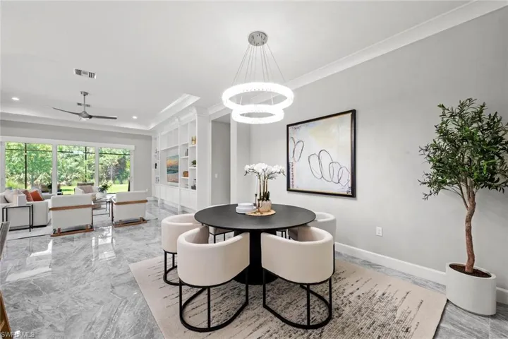 Dining space with ornamental molding, custom built in shelves entertainment center, recessed lighting