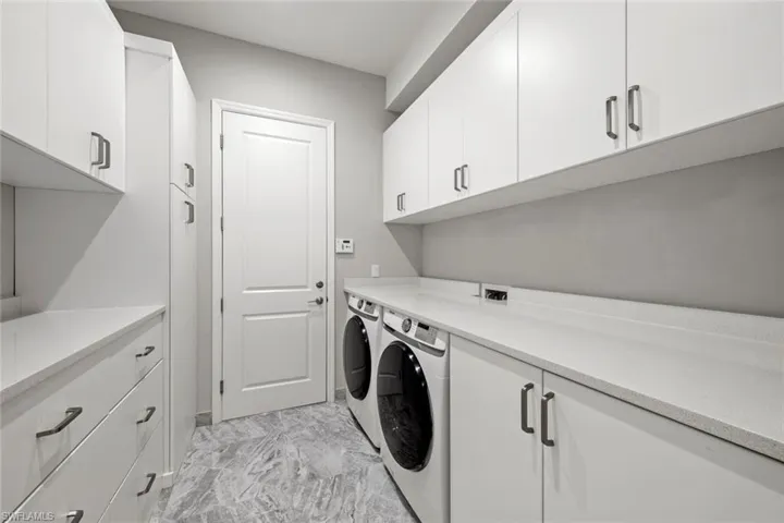 Amazing laundry space with front loading Samsung washer and dryer, custom built in cabinetry with ample storage, space for folding